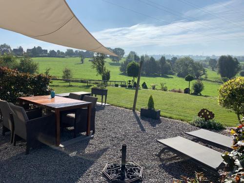 una mesa y sillas con vistas a un campo en Country house Au Ballet des Hirondelles en Herve