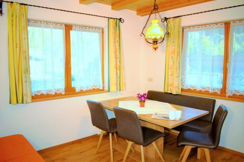 a dining room with a table and chairs and windows at Ferienwohnung Saalbach Fieberbrunn in Fieberbrunn