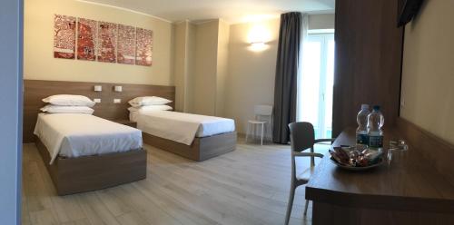 CastrezattoにあるTERRAZZA Roomsのベッド2台とテーブルが備わるホテルルームです。