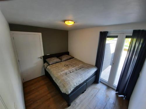 a small bedroom with a bed and a door at Landelijkhuisje in Deurne