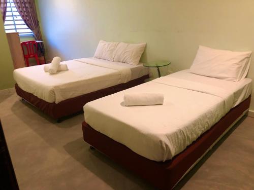 duas camas sentadas uma ao lado da outra num quarto em BUKIT INDAH HOMESTAY em Bentong