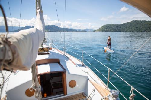 a man on a paddle board in the water on a boat at Angra House - Linda Casa em ILHA in Angra dos Reis