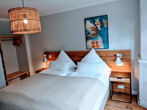 a bedroom with a white bed and a painting at Tetens Gasthof in Süderlügum