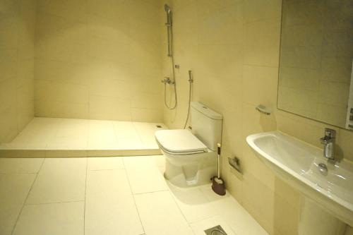 a white bathroom with a toilet and a sink at Beach Rose Tower in Seef