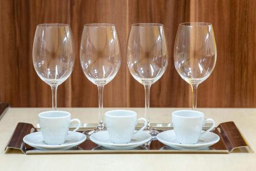 four wine glasses and cups on a tray on a table at Hostel Mayer Superior Veszprém in Veszprém