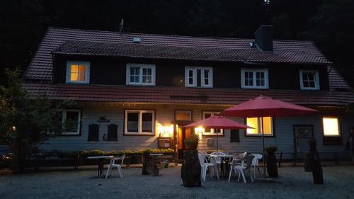 una casa con mesas y sombrillas delante en Waldpension Harzer Waldwinkel en Bad Grund