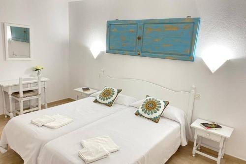 a white bedroom with a bed with a blue cabinet at PUERTAS AL MAR in Cala en Blanes