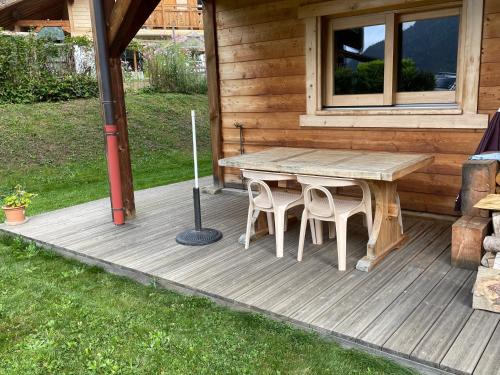 una terraza de madera con mesa y 2 sillas en Studio 1 pièce situé dans un chalet, en Beaufort