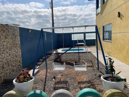 um quintal com um baloiço e uma piscina em PÉ NA AREIA apartamento térreo em Itapoá