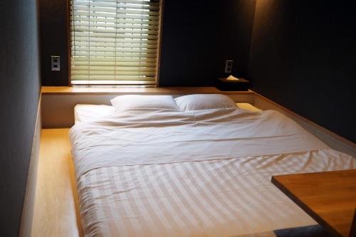 a large white bed in a room with a window at Yumoto Station Hotel MIRAHAKONE in Hakone
