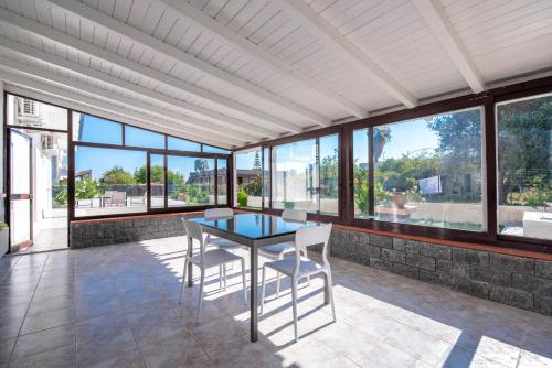 comedor con mesa de cristal y sillas blancas en Villa Orietta, en Fontane Bianche