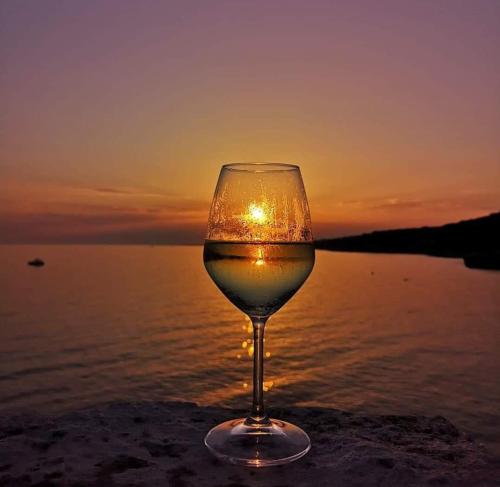 a glass of wine with the sunset in the background at Casa Cassiano in Patù