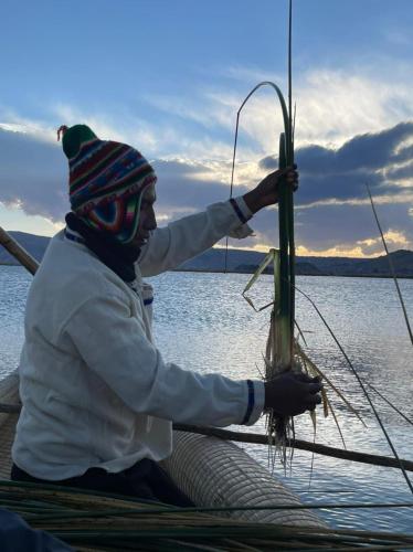 a man sitting on a boat holding a fishing pole at Uros Lodge Perú in Puno