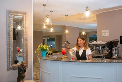 a woman standing behind a counter in a kitchen at Hotel President Sea Palace in Noto Marina