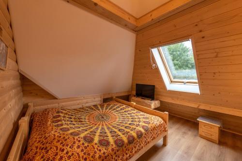 a bedroom in a log cabin with a bed and a window at Osada Sudecka in Lądek-Zdrój