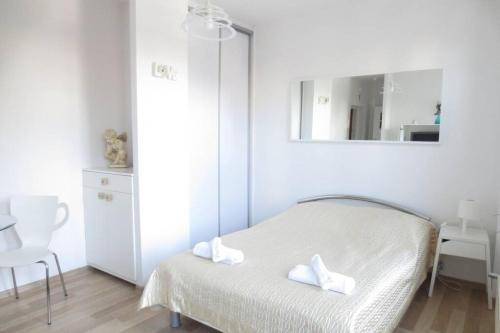 a white bedroom with a bed and a mirror at Apartment Ogarna 35/36 on the Gdańsk Old Town in Gdańsk