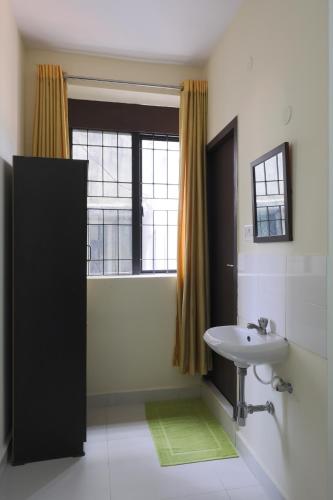 a bathroom with a white sink and a window at Green Tree Hotel - US Consulate Chennai in Chennai