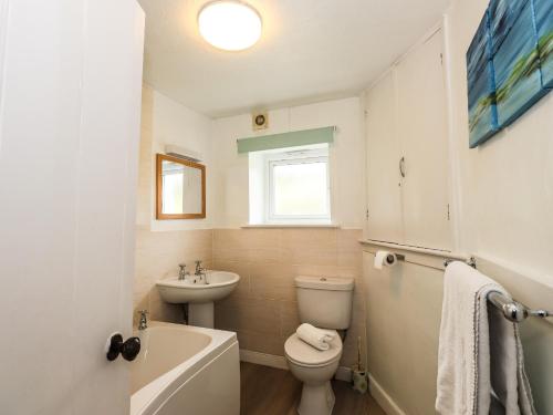 a white bathroom with a toilet and a sink at Hilber Cottage in Ambleside