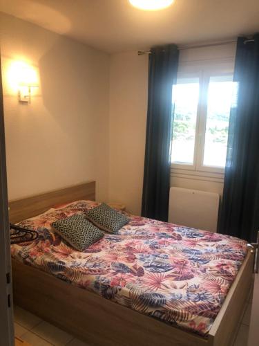 a bedroom with a bed with a floral bedspread and a window at T3 PIEDS DANS L'EAU CLIM WIFI TERRASSE VUE MER in Banyuls-sur-Mer