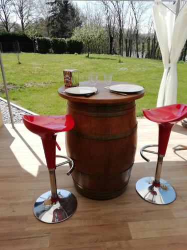 une table en tonneau de vin et deux tabourets rouges dans l'établissement AU CLOS DE L'ETANG, à Ravel