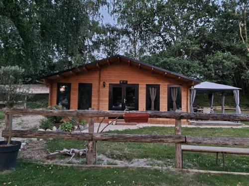 une maison en bois avec une clôture devant elle dans l'établissement Chalet Olivier, à Fléré-la-Rivière