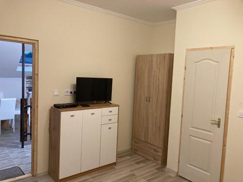a room with a tv on a cabinet and a door at Tisza-Holtág Apartman Tiszadada in Tiszadada