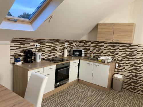 a kitchen with white cabinets and a brick wall at Tisza-Holtág Apartman Tiszadada in Tiszadada