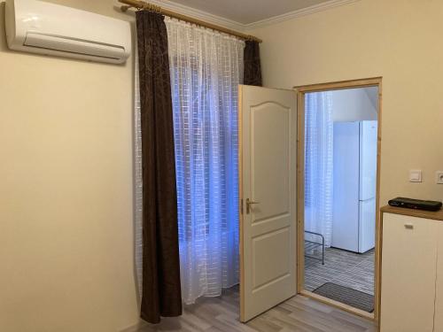 Habitación con puerta y ventana con cortinas. en Tisza-Holtág Apartman Tiszadada, en Tiszadada