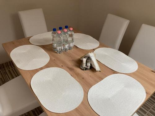 una mesa de madera con platos blancos y botellas de agua en Tisza-Holtág Apartman Tiszadada en Tiszadada