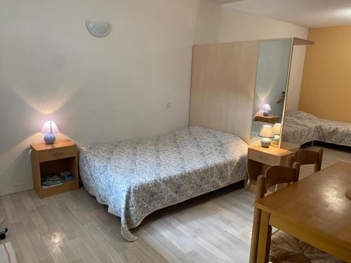 een slaapkamer met een bed, 2 tafels en een spiegel bij Studio Tabagnoz in Prémanon