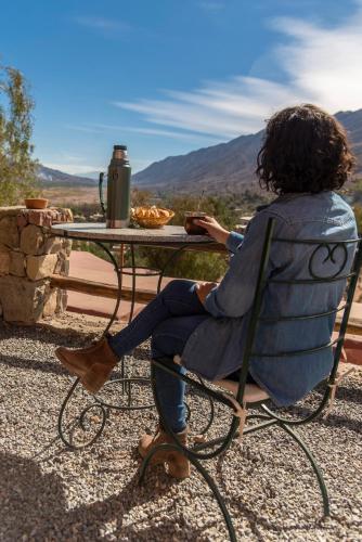a woman sitting in a chair at a table at Villa del Cielo in Tilcara