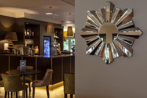 a restaurant with a bar with a clock on the wall at Best Western Plus Pinewood Manchester Airport-Wilmslow Hotel in Handforth