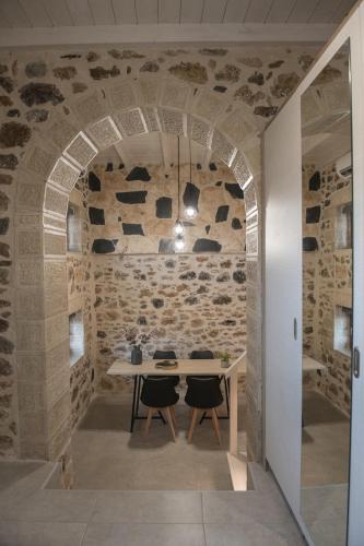 a dining room with a table and a stone wall at Petrino in Sisi with private pool and garden in Sissi