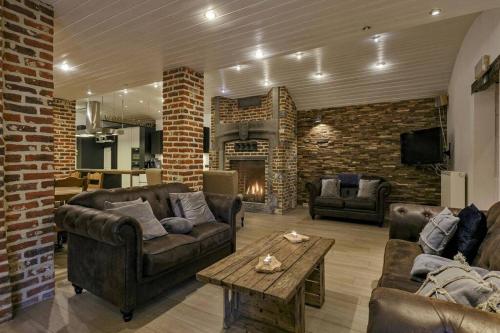 a living room with leather furniture and a fireplace at Domein Warandehof in Gooik