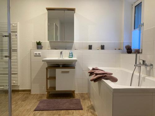 a white bathroom with a tub and a sink at Ferienwohnung Sonnenblick in Hohnstein