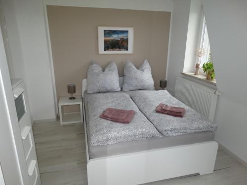 a white bedroom with a large white bed with two pillows at Ferienwohnung Sonnenblick in Hohnstein