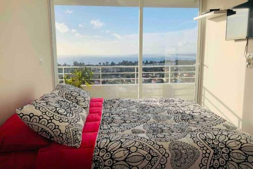 una camera da letto con un letto e una grande finestra di Espectacular depto con vista al mar en Concón a Concón