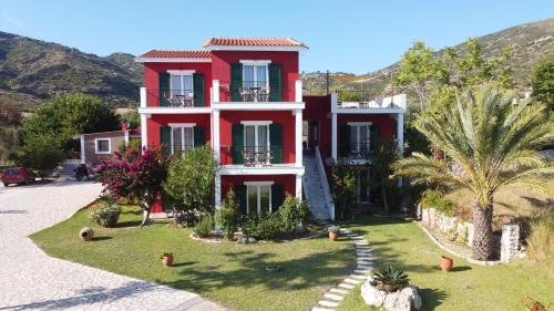 a red house with palm trees in front of it at Kykeon Studios in Katelios