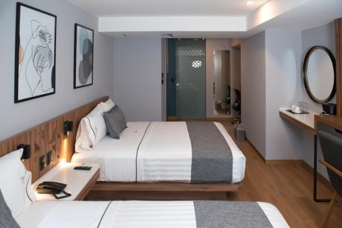 a hotel room with two beds and a mirror at Hotel Flamencos Centro Histórico in Mexico City