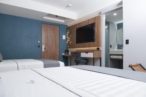 a hotel room with two beds and a flat screen tv at Hotel Flamencos Centro Histórico in Mexico City