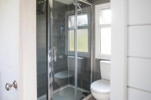 uma casa de banho com um WC e uma cabina de duche em vidro. em Brondini View Cabin (Private Garden and Hot Tub) em Brondini