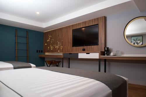 a hotel room with two beds and a flat screen tv at Hotel Flamencos Centro Histórico in Mexico City