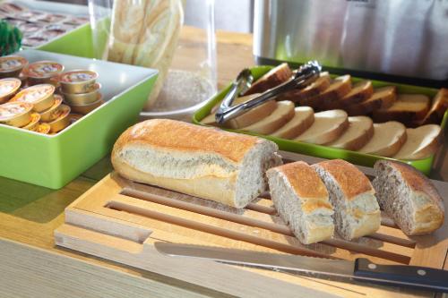 a cutting board with bread and other food on a table at ibis budget Pontarlier in Pontarlier