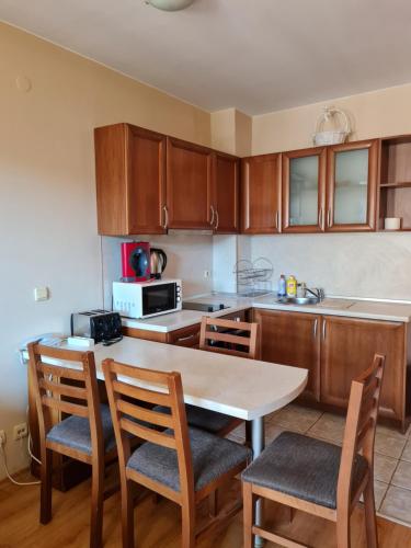 una cocina con armarios de madera, mesa y sillas en Edelweiss Inn Apartment 20, en Bansko