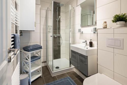 Un baño blanco con ducha y lavabo. en GREATsiel - die großartige Ferienwohnung in Greetsiel, en Greetsiel