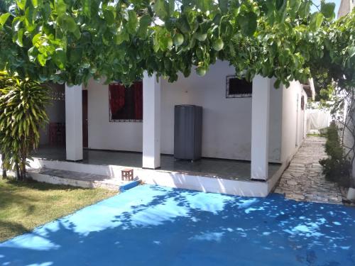 a pool in front of a house with a tree at Paracuru HolaOnda WaveHostel in Paracuru