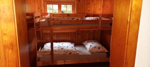 Łóżko piętrowe w drewnianym pokoju z 3 łóżkami piętrowymi w obiekcie Chalet bois soleil w mieście Les Mosses