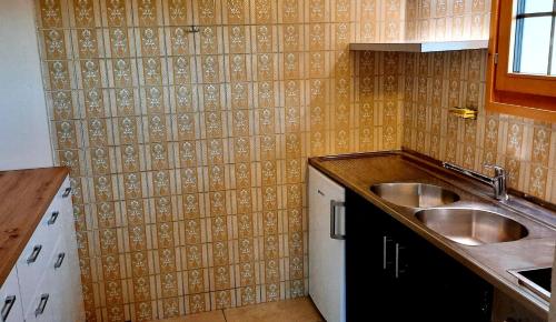 a kitchen with a sink and a tiled wall at Chalet bois soleil in Les Mosses