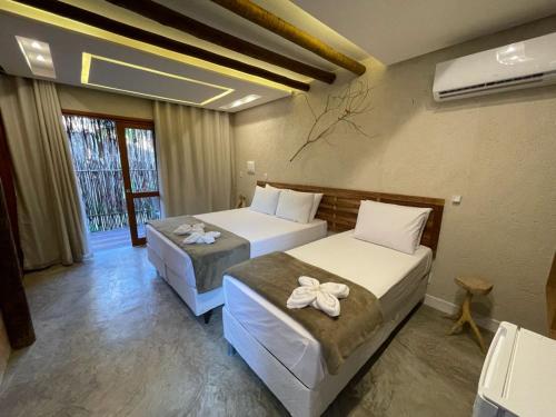 a hotel room with two beds and a window at Naim Milagres in São Miguel dos Milagres