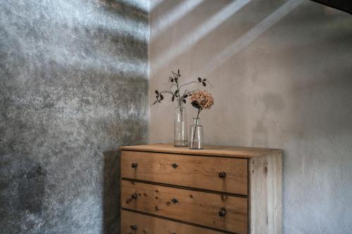 a wooden dresser with a vase of flowers on it at St. Vigilius modern historic apartments in Nalles